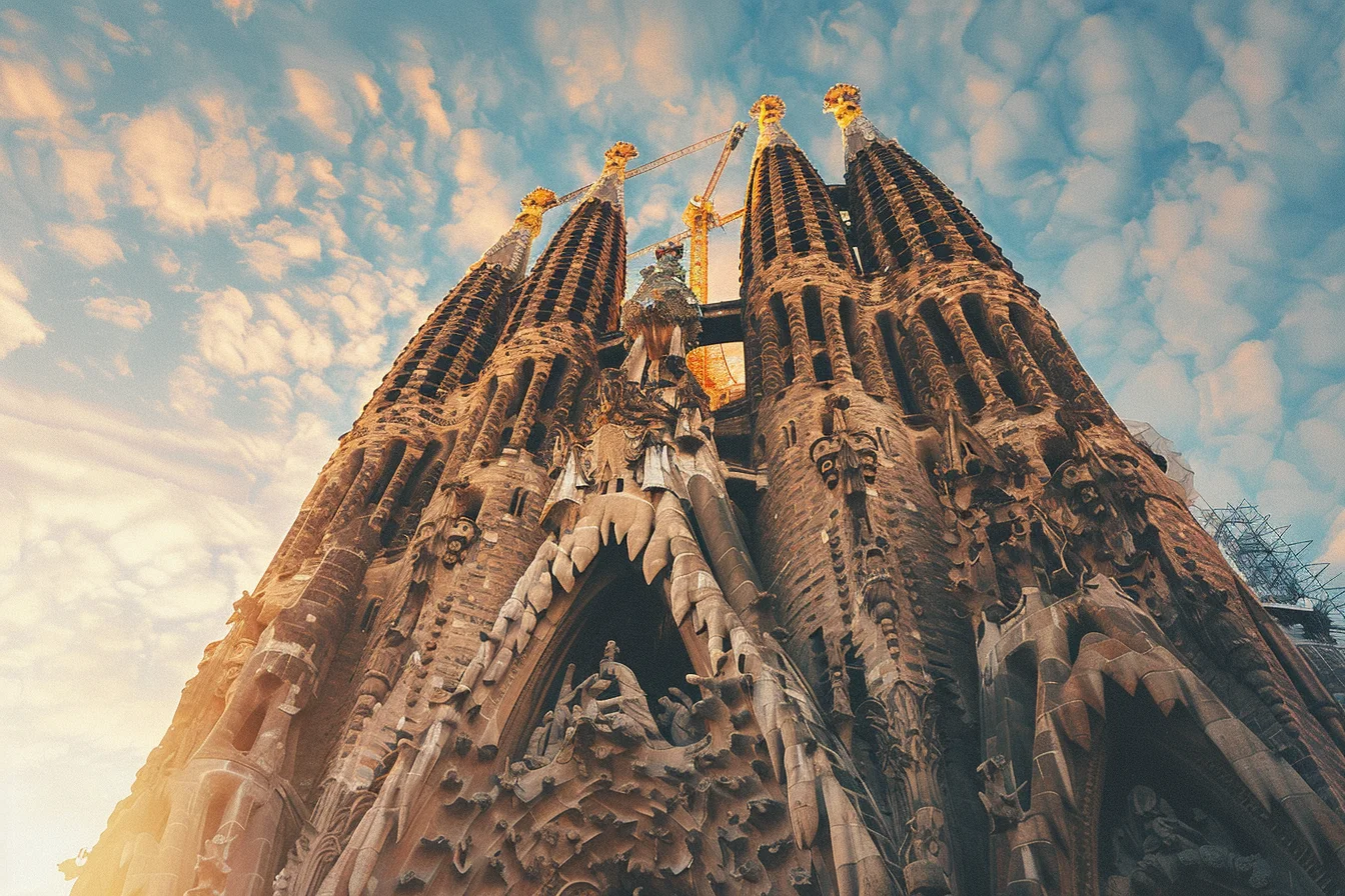 La Sagrada Família basilica in Barcelona at golden hour — Gaudí stone spires rising against warm amber sky, intricate carved facade detail visible