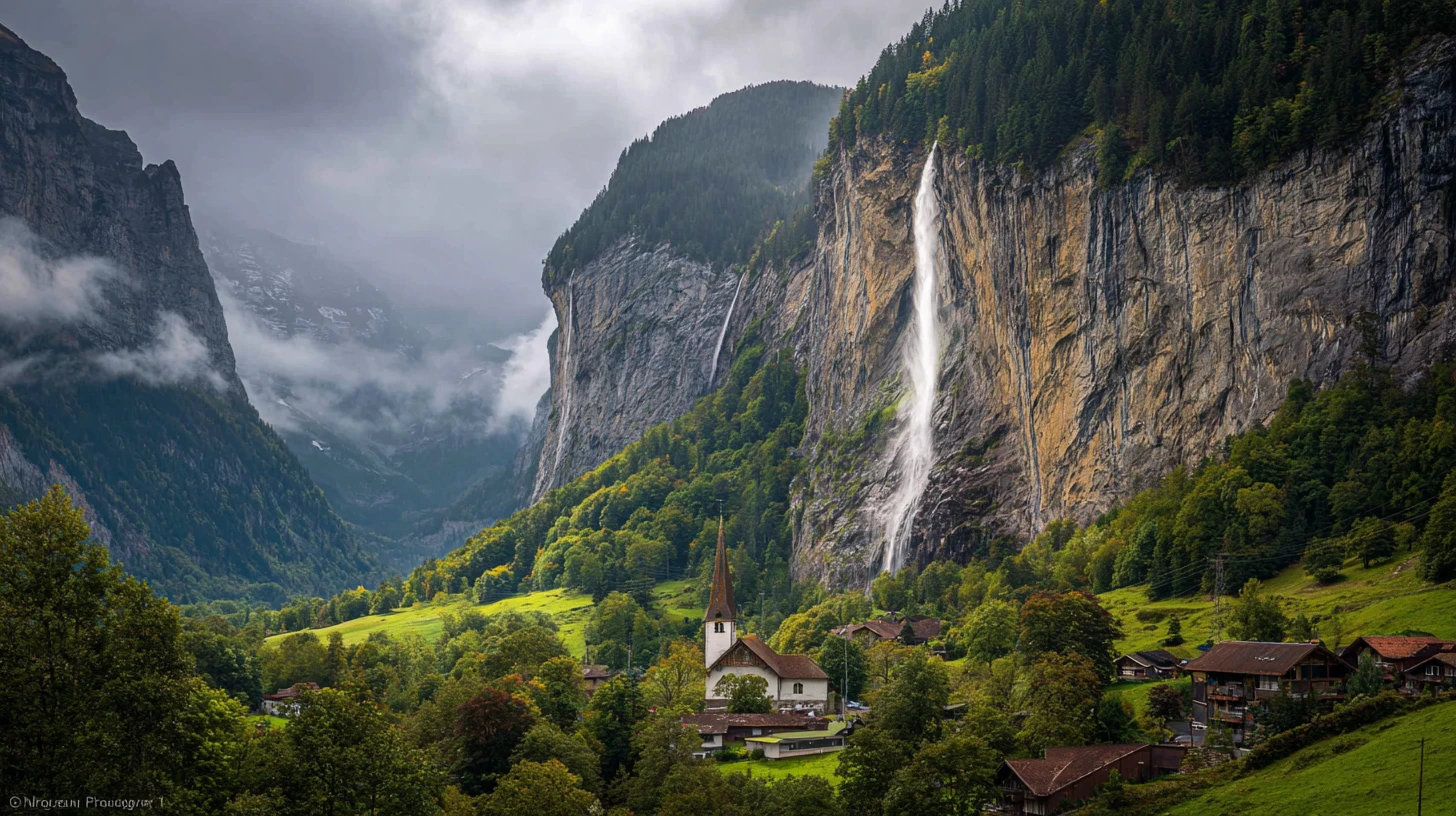 The Staubbach Falls free-falling nearly 300 metres down the sheer cliff of the Lauterbrunnen valley, alpine meadow and timber chalets below — the postcard image of the Bernese Oberland's mountain-village character and its dairy-and-cheese alpine table